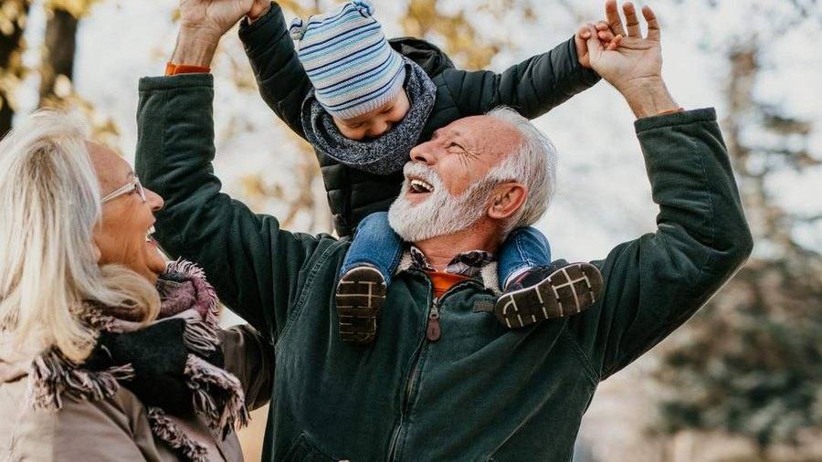 Abuelos jugando con su nieto al aire libre durante una visita a Canadá